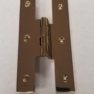 May include: A pair of gold-toned metal door hinges with four screw holes on each side.