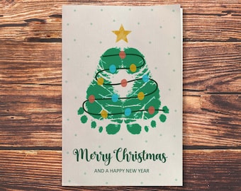 May include: A Christmas card with a green handprint tree with a yellow star on top and colorful ornaments. The card reads "Merry Christmas and a Happy New Year".