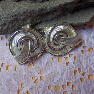 May include: A pair of silver tone clip-on earrings with a twisted design.