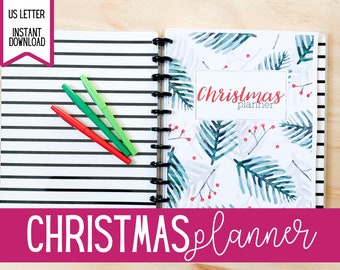 Op de afbeelding: Een witte planner met een aquarelontwerp van groene dennentakken en rode bessen. De planner heeft de titel "Christmas planner".