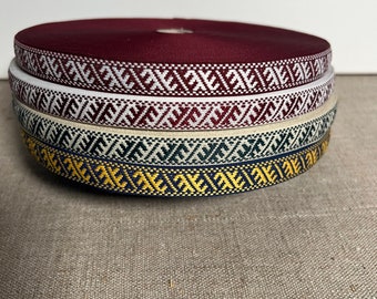 May include: Four rolls of patterned trim in burgundy, white, beige, and navy blue with gold accents. The trim has a geometric design.