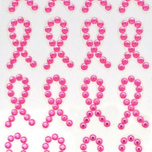 May include: Pink ribbon stickers made of rhinestones. Each sticker is about 1 inch wide and features a pink ribbon design.