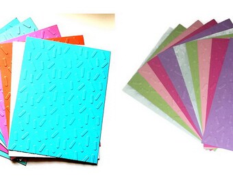 May include: A collection of colorful cardstock sheets with a textured pattern. The sheets are fanned out, showcasing a variety of colors including blue, pink, orange, and white. The textured pattern consists of small, raised dashes.