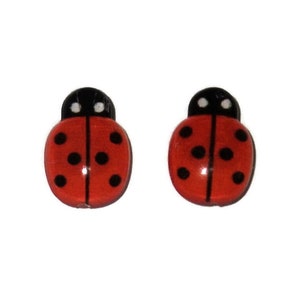 May include: A pair of red ladybug earrings with black spots and white accents.