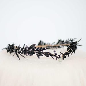 May include: A black floral crown with small black berries. The crown is made of faux flowers and berries and is perfect for a gothic or dark wedding.