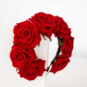 May include: A red rose flower crown headband. The headband is made of a flexible wire base and is decorated with red roses.