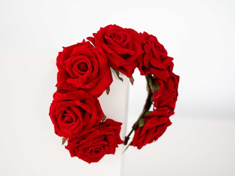 May include: A red rose flower crown headband. The headband is made of a flexible wire base and is decorated with red roses.