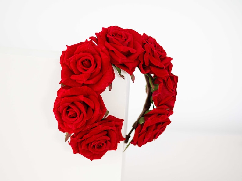 May include: A red rose flower crown headband. The headband is made of a flexible wire base and is decorated with red roses.