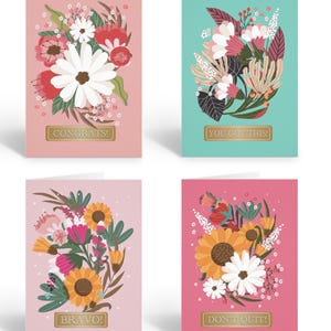 May include: Set of four greeting cards with floral designs and gold lettering. The cards feature pink, red, yellow, and white flowers on a pink, blue, or green background. The text on the cards reads "Congrats!", "You Got This!", "Bravo!", and "Don't Quit!"