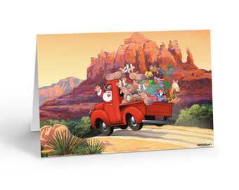 May include: A Christmas-themed greeting card featuring a red truck driven by Santa Claus and reindeer, loaded with gifts, driving through a desert landscape with red rock formations. The card is white.
