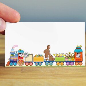May include: A colorful Easter train with bunnies, chocolate eggs, and baskets. The train is made of cardboard and has a white background.