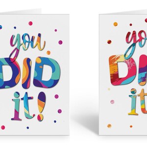 May include: Two white greeting cards with colorful text that reads "you did it!" The text is in a layered, abstract style with a variety of colors, including red, orange, yellow, green, blue, purple, and pink. The cards are decorated with small white dots.
