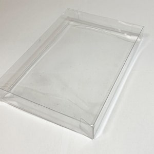 May include: Clear plastic box with a rectangular shape. The box is empty and has a smooth, glossy finish.