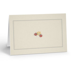 May include: A blank, off-white card with a black border. The card has a small, yellow flower with two red ladybugs on it.