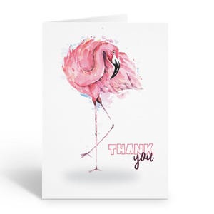 May include: A folded greeting card featuring a watercolor illustration of a pink flamingo. The flamingo is standing on one leg with its head tucked in. The words "THANK you" are printed in pink and purple.