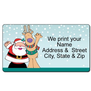 May include: A rectangular label with a cartoon Santa Claus and reindeer on a light blue background with falling white snowflakes. The label includes the text: "We print your Name Address & Street City, State & Zip."