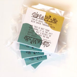 May include: Packaged cards with text: "FOR BY GRACE YOU HAVE BEEN SAVED THROUGH FAITH. AND THIS IS NOT YOUR OWN DOING; IT IS THE GIFT OF GOD, NOT A RESULT OF WORKS, SO THAT NO ONE MAY BOAST. EPHESIANS 2:8-9." The cards have a teal and gold color scheme with floral accents.