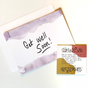 May include: A white greeting card with a watercolor design in shades of purple and the words "Get well Soon!" in black. A small square card with a floral design and text from Romans 8:28 is also present.