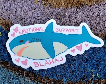 May include: A blue and white shark sticker with pink hearts and the text "Emotional Support Blåhaj".