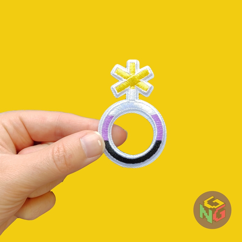 hand holding nonbinary embroidered patch in front of yellow background