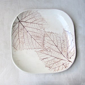 May include: A white ceramic serving platter with a brown leaf design. The leaves are delicate and intricate, and the platter is perfect for serving appetizers or desserts.