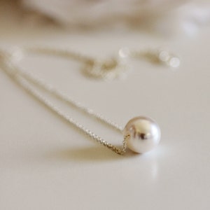 May include: A simple silver chain necklace with a single large white pearl pendant.