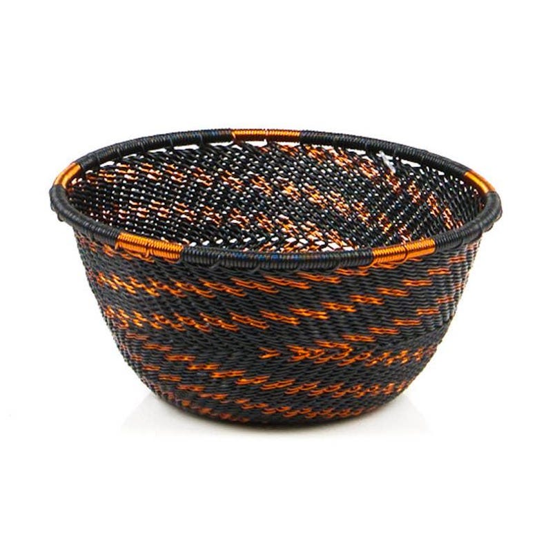 May include: A woven basket with a round shape, featuring a black and orange pattern. The basket's rim is reinforced with a darker material and accented with orange. This decorative basket is suitable for storage or display.