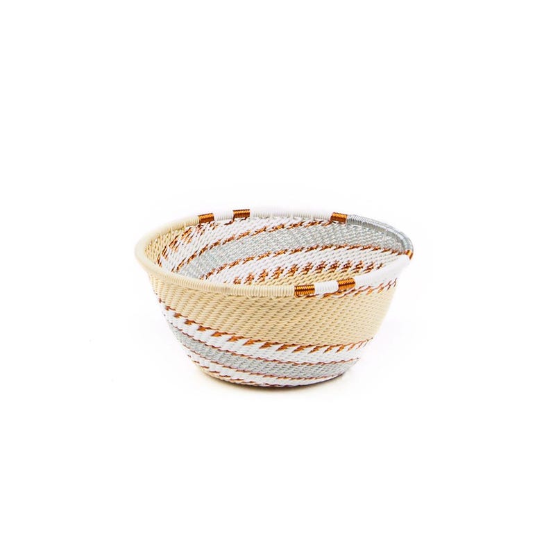 May include: A woven basket with a round shape and a cream-colored base. The basket features a spiral design with alternating bands of gray, white, and orange. The rim and accents are orange.