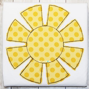 May include: A yellow sun with a polka dot pattern. The sun has eight rays and is outlined in black.