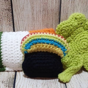 May include: Crocheted Irish-themed decorations, including a green shamrock, a pot of gold with a rainbow, and a green, white, and orange pillow.