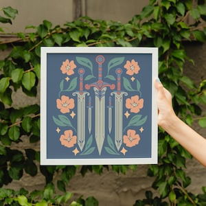 May include: A framed print featuring three stylized swords with floral and leaf accents in peach, green, and blue. The swords are centered on a dark blue background, surrounded by peach-colored flowers and green leaves.