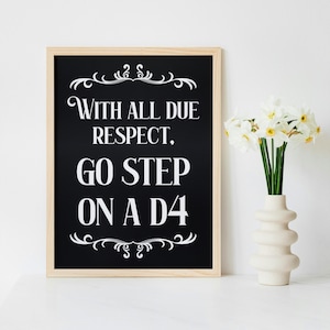 Puede incluir: Una impresión en blanco y negro enmarcada con el texto "WITH ALL DUE RESPECT, GO STEP ON A D4". La impresión está en un marco de madera clara y se muestra sobre una superficie blanca. Un jarrón con flores blancas está al lado de la impresión.