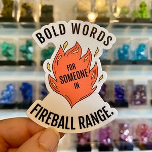 May include: White sticker with black text that reads "Bold Words for Someone in Fireball Range." The sticker features a red and orange flame design.