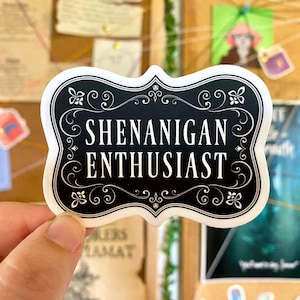 May include: A black and white sticker with a decorative border and the text "Shenanigan Enthusiast".