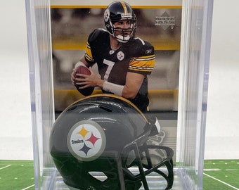 Peut inclure: Un mini casque de football américain des Steelers de Pittsburgh noir et jaune dans une vitrine en plastique transparente avec une carte de football d'un joueur en uniforme des Steelers.