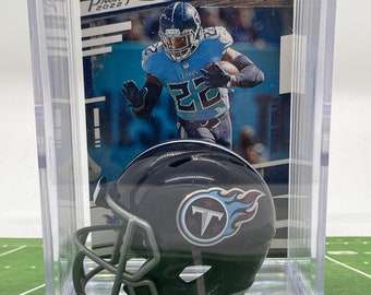 May include: A clear plastic display case with a black and blue miniature football helmet inside. The helmet has a white "T" logo with a blue flame design. The case also includes a trading card featuring a football player in a blue jersey with the number 22.