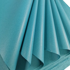 May include: A stack of teal blue tissue paper, folded and fanned out, showing the texture and colour of the paper.