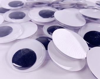 Könnte beinhalten: Ein Haufen Glitz Augen mit schwarzen Pupillen und weißen Skleren. Die Augen sind aus Kunststoff und haben eine selbstklebende Rückseite.