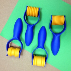 May include: Three blue and yellow plastic rollers with a textured surface. The rollers are designed for crafting and are ideal for creating patterns in clay or dough.