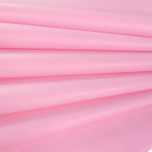 May include: Pink tissue paper folded in a fan shape. The paper is smooth and has a slight sheen.