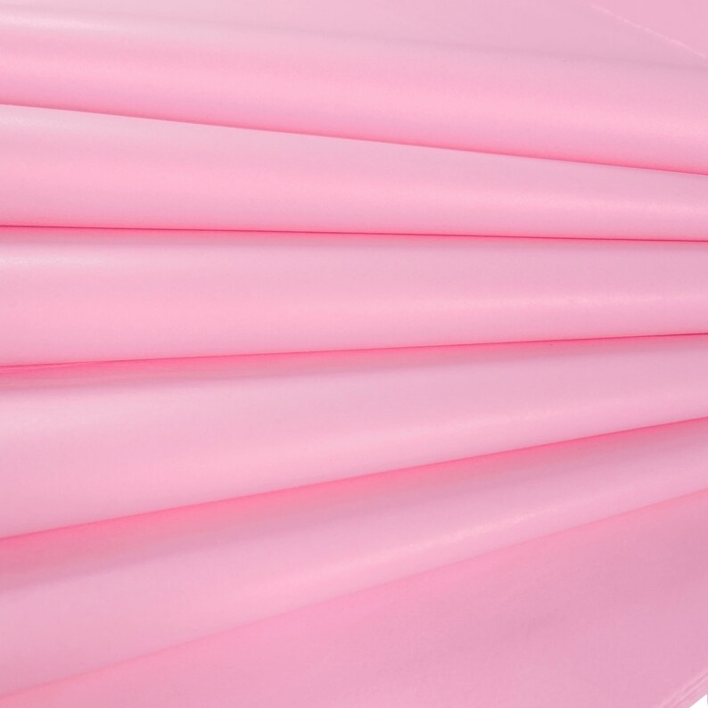 May include: Pink tissue paper folded in a fan shape. The paper is smooth and has a slight sheen.