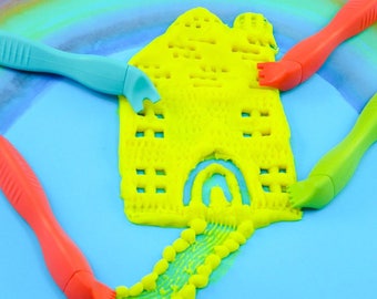 May include: A yellow play dough castle with a bridge and green, red and blue play dough tools.