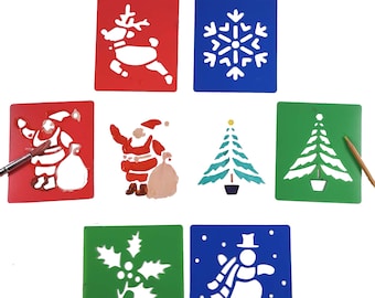 May include: Set of 8 Christmas stencils for painting. The stencils are made of plastic and feature various holiday designs, including Santa Claus, a reindeer, a snowman, a snowflake, a Christmas tree, and a holly leaf.