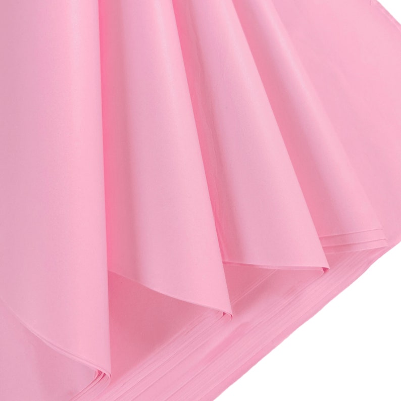 May include: A stack of pink tissue paper, folded and arranged in a fan shape. The paper is soft and delicate, with a subtle sheen.