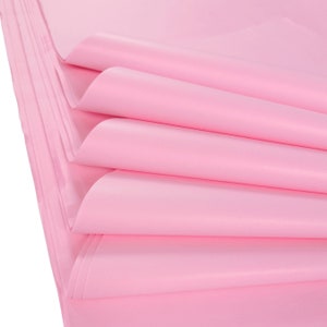 May include: Stack of pink tissue paper, folded and layered, showing the soft texture and delicate color.