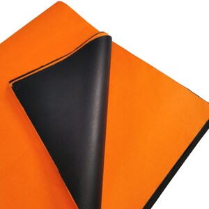 May include: A bright orange fabric sheet with a black backing. The sheet is folded over, revealing the black backing.