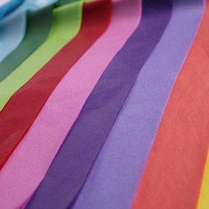May include: A collection of colourful tissue paper sheets in various shades of blue, green, red, pink, purple, and orange. The tissue paper is arranged in a fan shape, with the colours blending together.