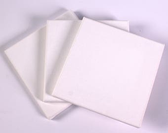 Könnte beinhalten: Drei weiße Leinwandplatten, bereit zum Malen. Die Platten sind übereinander gestapelt, wobei die oberste Platte leicht nach rechts versetzt ist.