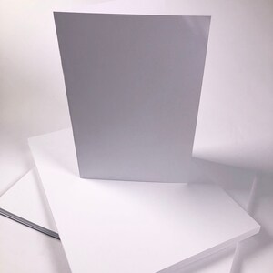 Puede incluir: Una pila de papel de cartulina blanca. La hoja superior est&aacute; de pie.