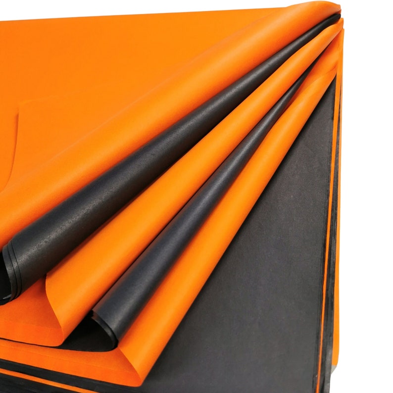 May include: A stack of orange and black tissue paper. The paper is folded in a way that shows the different colors.
